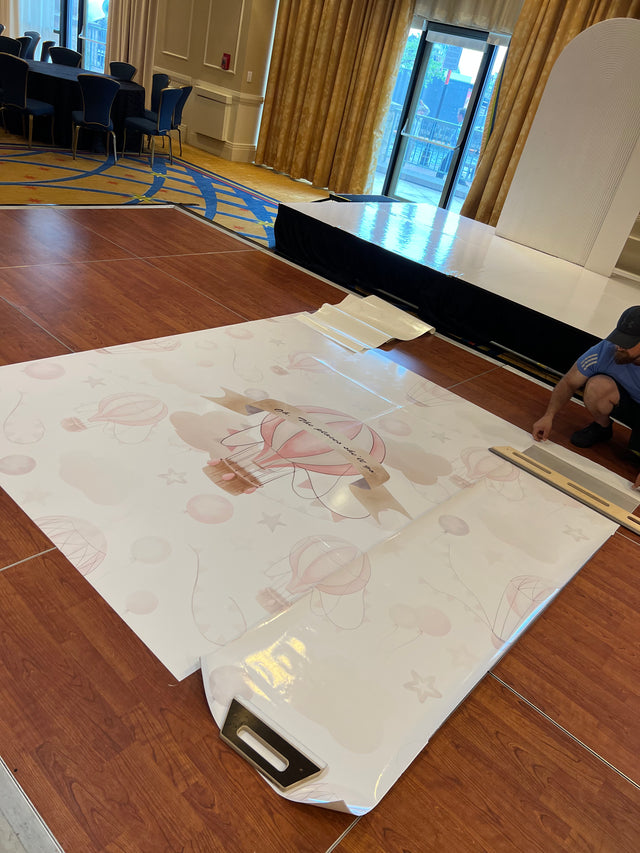 Installation of custom floor wraps with hot air balloon design on wooden floor in event space