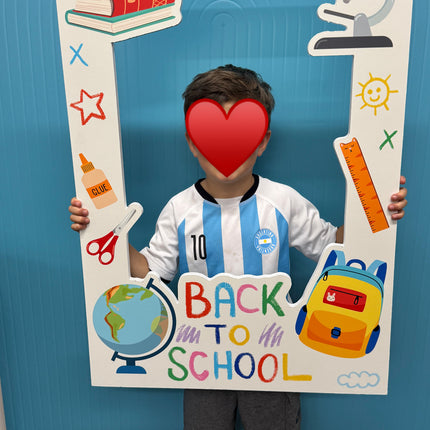 Child holding a WPE Production backdrop with a colorful back to school photo frame for 2025-2026 school year