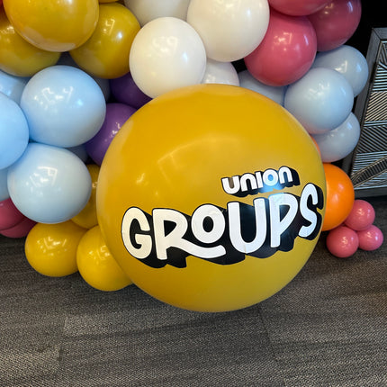 Yellow balloon with custom balloon stickers spelling union groups surrounded by colorful balloon cluster