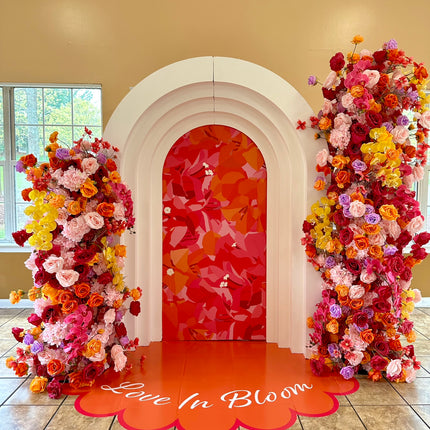 Colorful floral arch backdrop with the phrase Love In Bloom on custom die cut floor adhesive