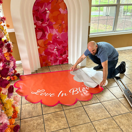 Man applying custom die cut floor adhesive with a floral design in a bright indoor setting