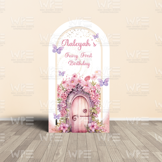 Personalized fairy first birthday backdrop with pink floral arch, butterflies, and wooden door decoration