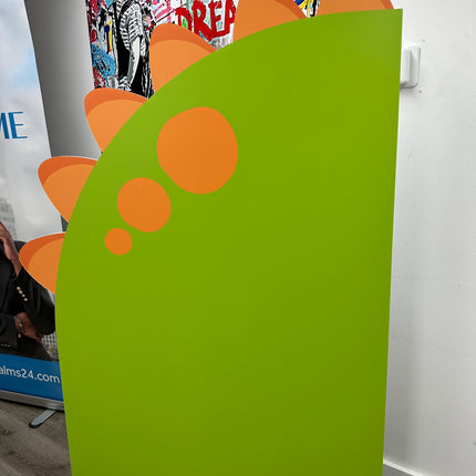 Green custom foam backdrop printing with orange circular and spike design standing indoors