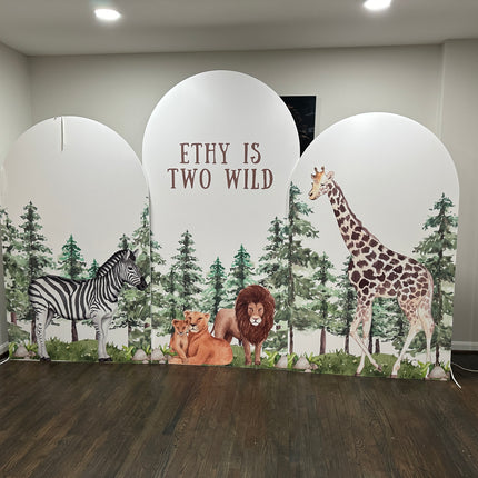 Custom foam backdrop printing with wild animal design including zebra, lions, and giraffe in a forest setting for birthday party decor