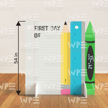 Custom paper cutout for events featuring giant pencil, ruler, crayon, and notebook design on wooden floor
