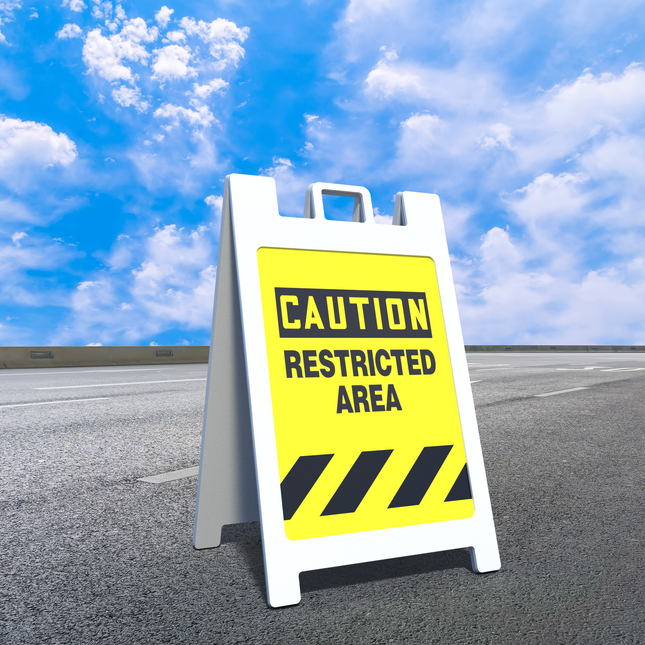 White A frame sign with yellow caution restricted area custom sign inserts for A frame on pavement under blue sky