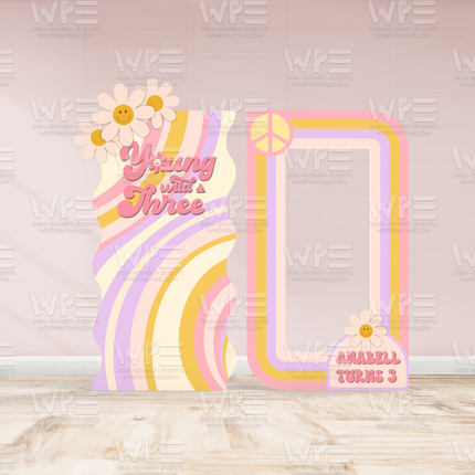 Colorful groovy birthday backdrop decorations with pastel rainbow stripes and peace sign for a third birthday party
