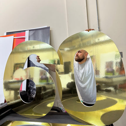 Large metallic number display gold reflective 60 with person holding in event space